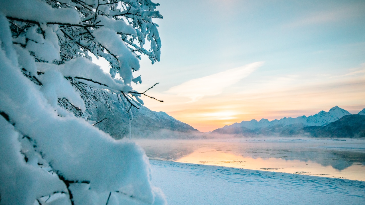 A winter sunset reflects across flowing water in Haines, Alaska.